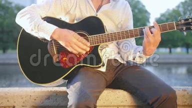 人坐在公园里的石砌木板路上弹吉他.. 近距离射击。
